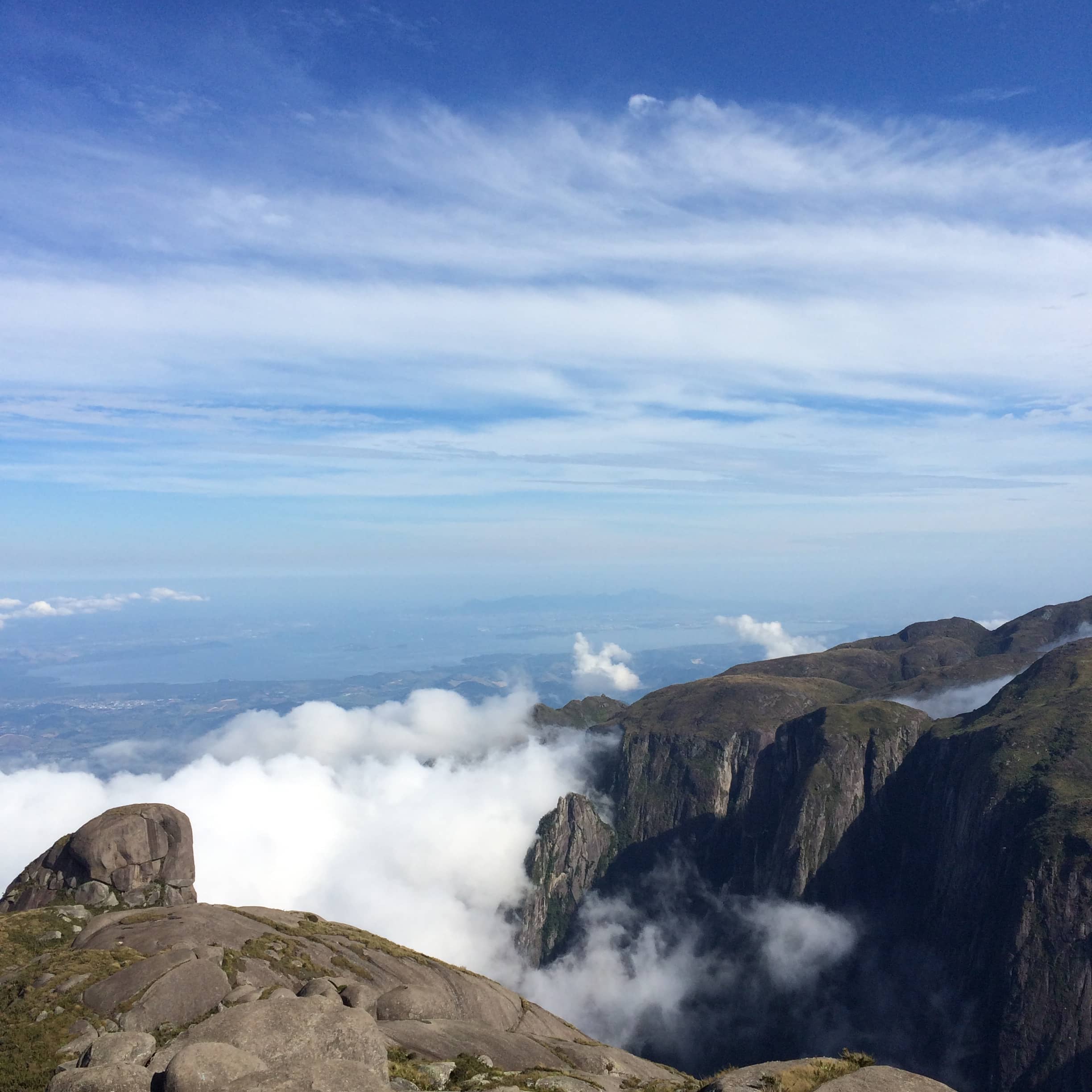 Rocky ridges overlook a valley filled with clouds.