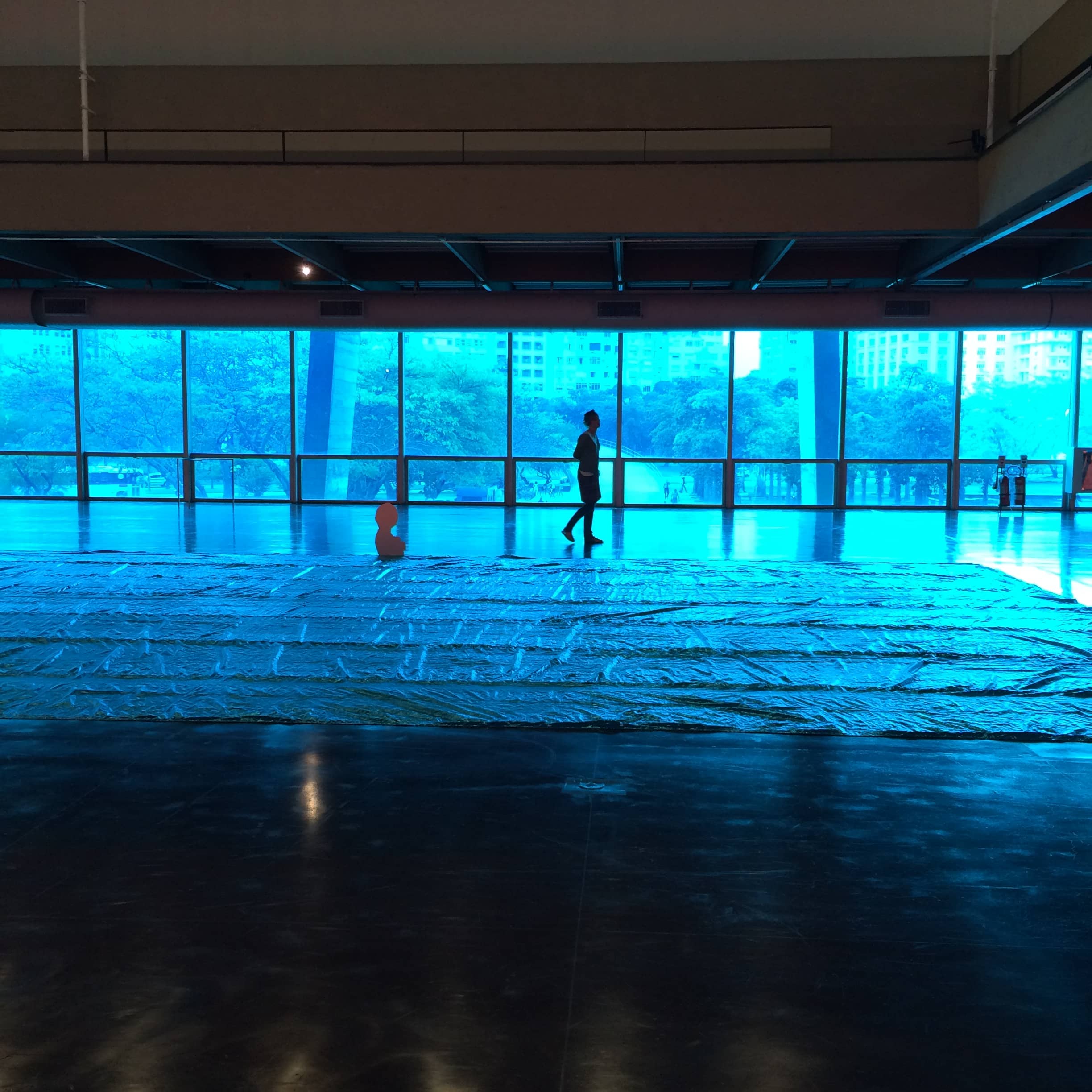 Blue light fills a glass-walled interior and reflects across the floor.
