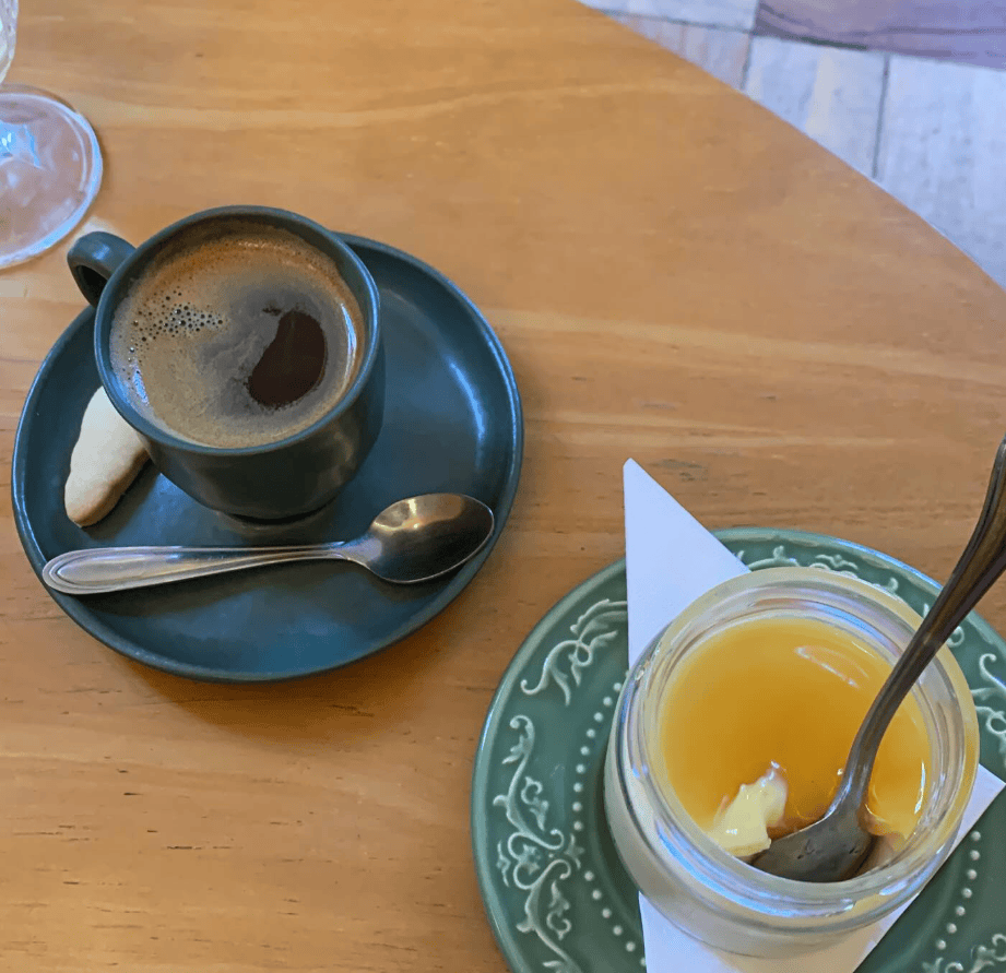 A cup of coffee and a glass of orange juice rest on a wooden table.