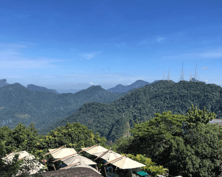 Small rooftops sit below a panorama of green mountain ridges.