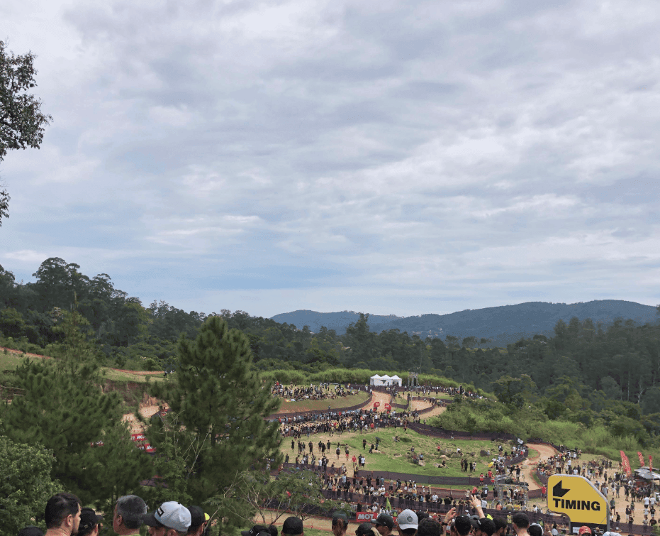 A crowd overlooks a cycling venue spread across a green valley.