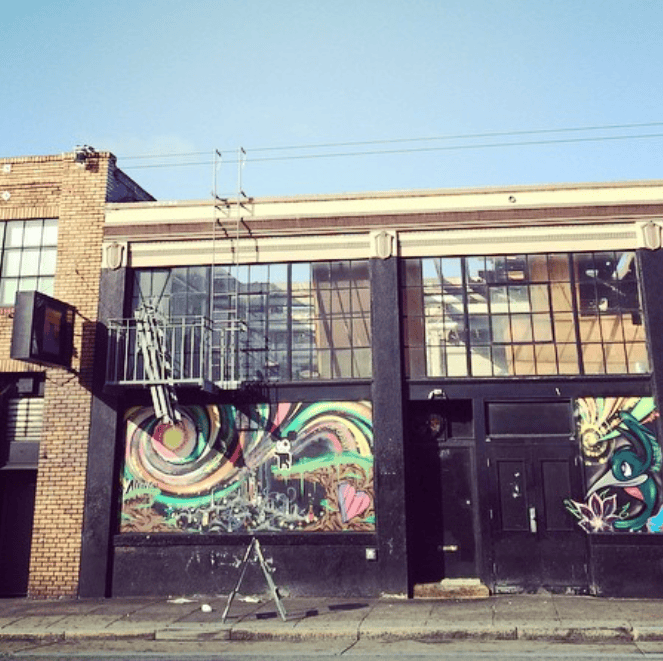 Colorful painted panels decorate the lower windows of an industrial building.