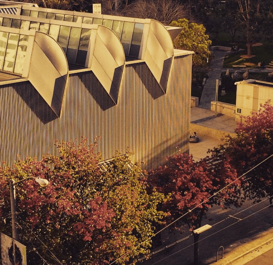 Angular concrete forms cast shadows above a planted walkway.