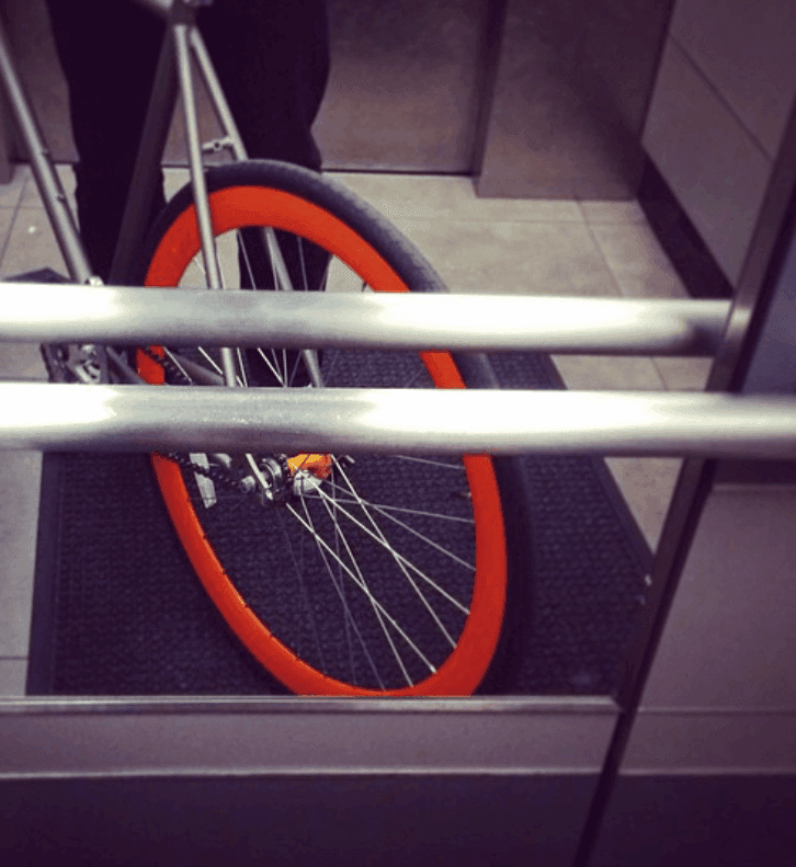 A bicycle wheel and frame sit behind metal rails inside a transit vehicle.